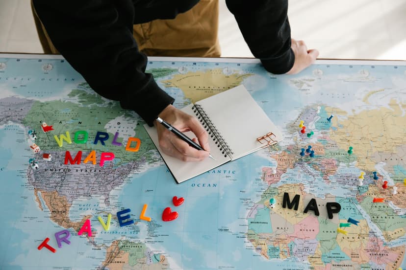 A person planning a trip, sitting at a table with a world map spread out.