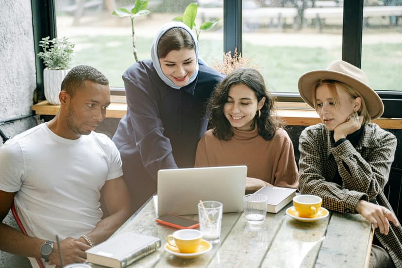 Group of people sitting at a table in front of laptop discussing about there travel plan