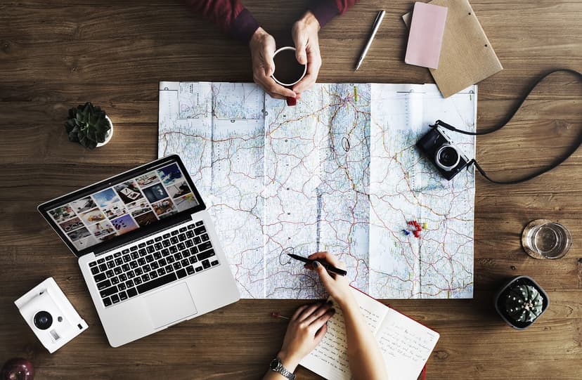 Two people planning a trip together, looking at a map and using a laptop.